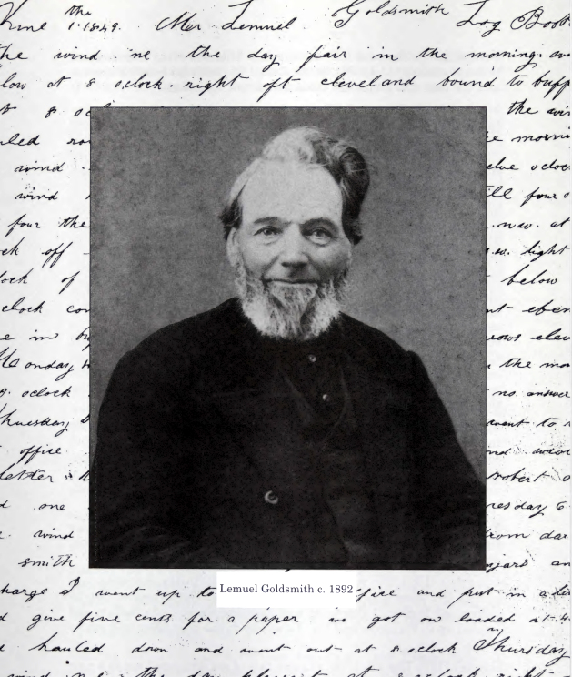 An 1892 portrait of Lemuel Goldsmith. He is about 66 years old. He has dark hair mixed with grey and a light grey beard. He’s wearing a dark jacket over a dark vest and shirt. He is grinning.