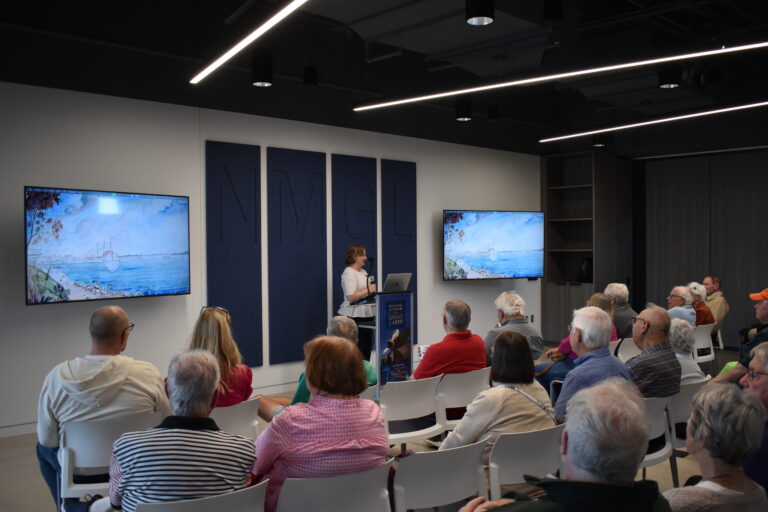 Woman at a podium in front of a crowd of people.